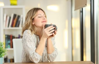 Portrait of a woman breathing and holding a coffee mug at home