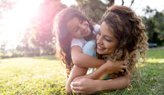 Beautiful portrait of a Latin American mother playing with her daughter outdoors and hugging - family concepts