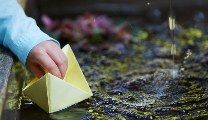 Boy Playing with Paper Boat in Water