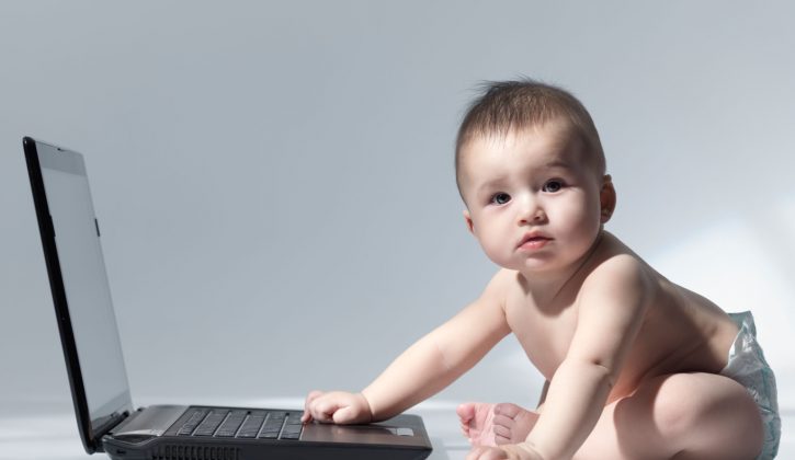 Six month old baby sitting in front of a laptop computer
